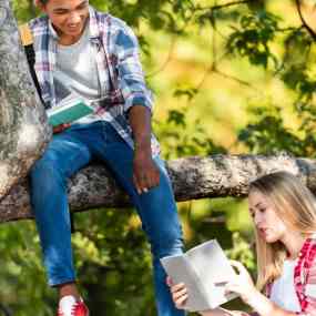 two teens reading in a tree