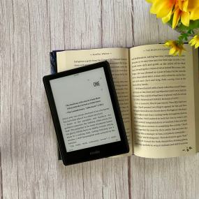 a kindle lies in the middle of a book's pages