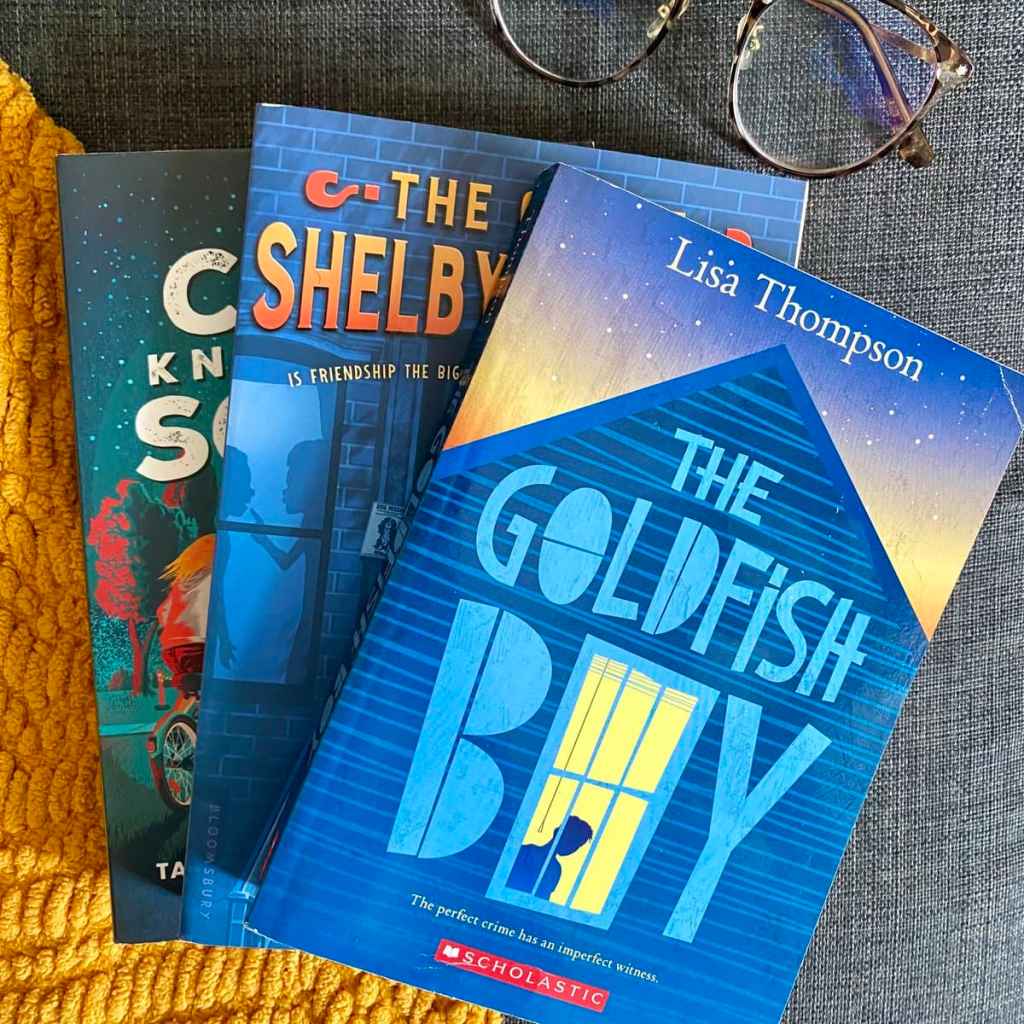 a stack of mystery books for middle schoolers including the goldfish boy, shelby holmes, and coop knows the scoop