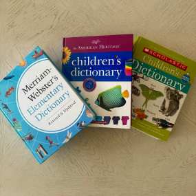 three kids dictionaries lie on a plain surface