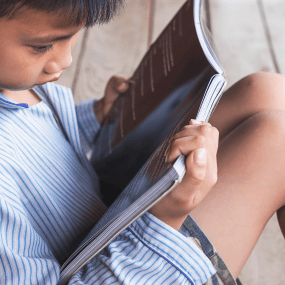 a boy in striped pajamas reads a kids magazine